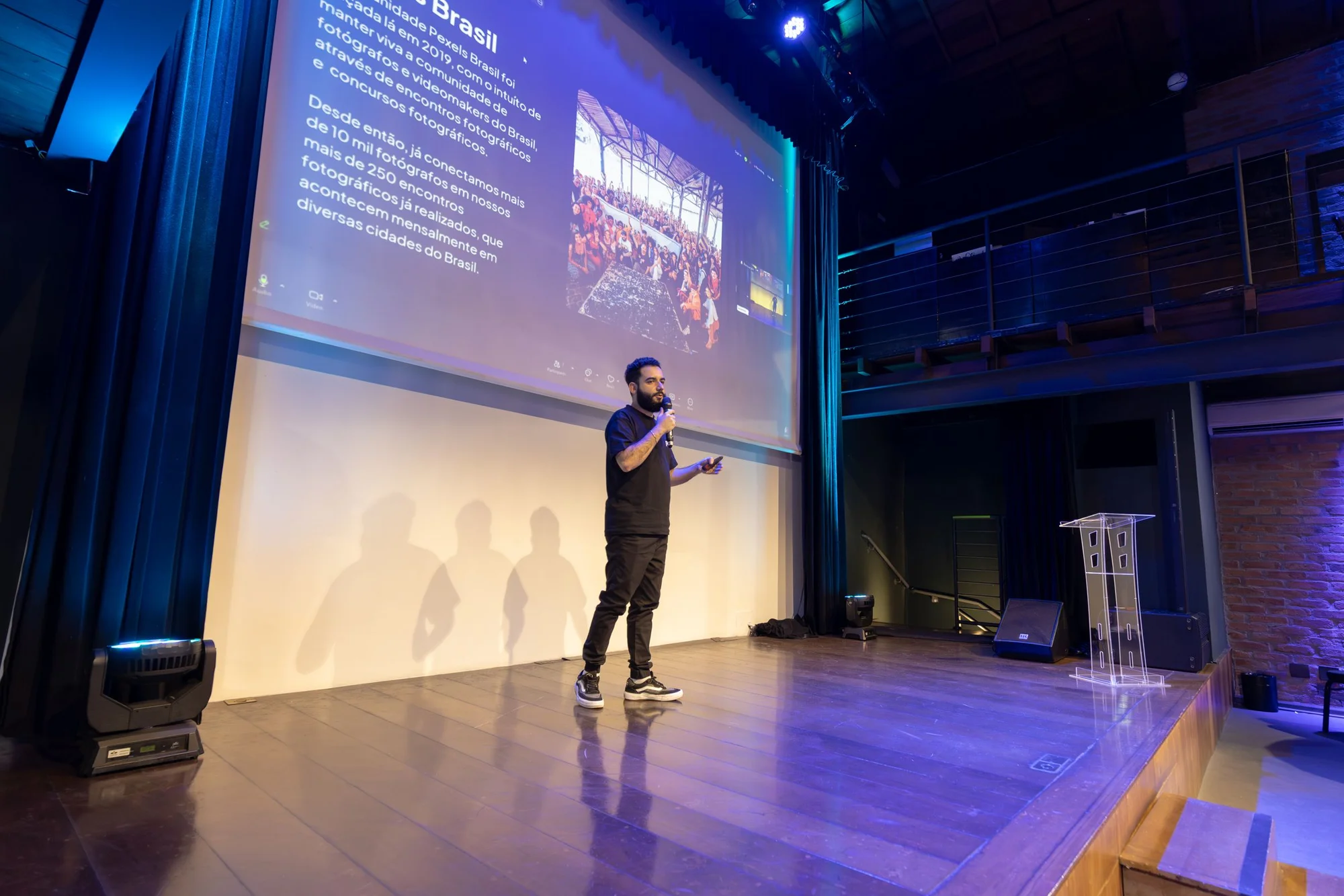 A presenter using a microphone and projection screen at a conference