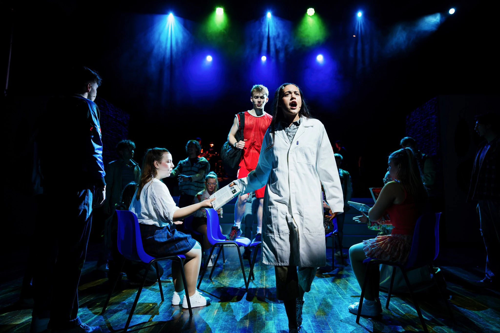 Performers lit with white front light and blue and green stage lighting
