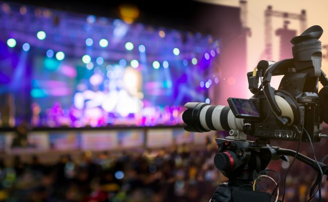 Video production covering event on stage by professional video camera in outdoor concert at sunset